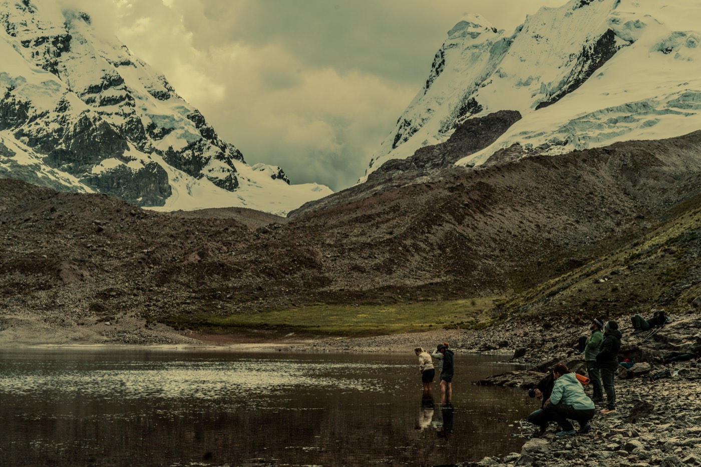 Participantes se acercan al agua de una laguna bajo los glaciares.