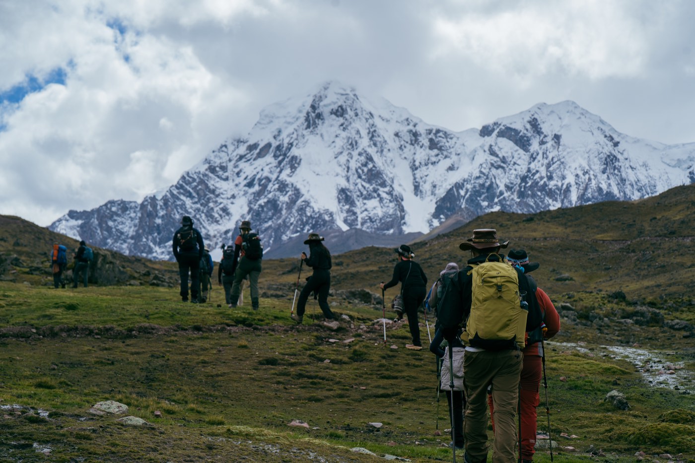 Los peregrinos avanzan por el sendero de regreso frente a las montañas nevadas.