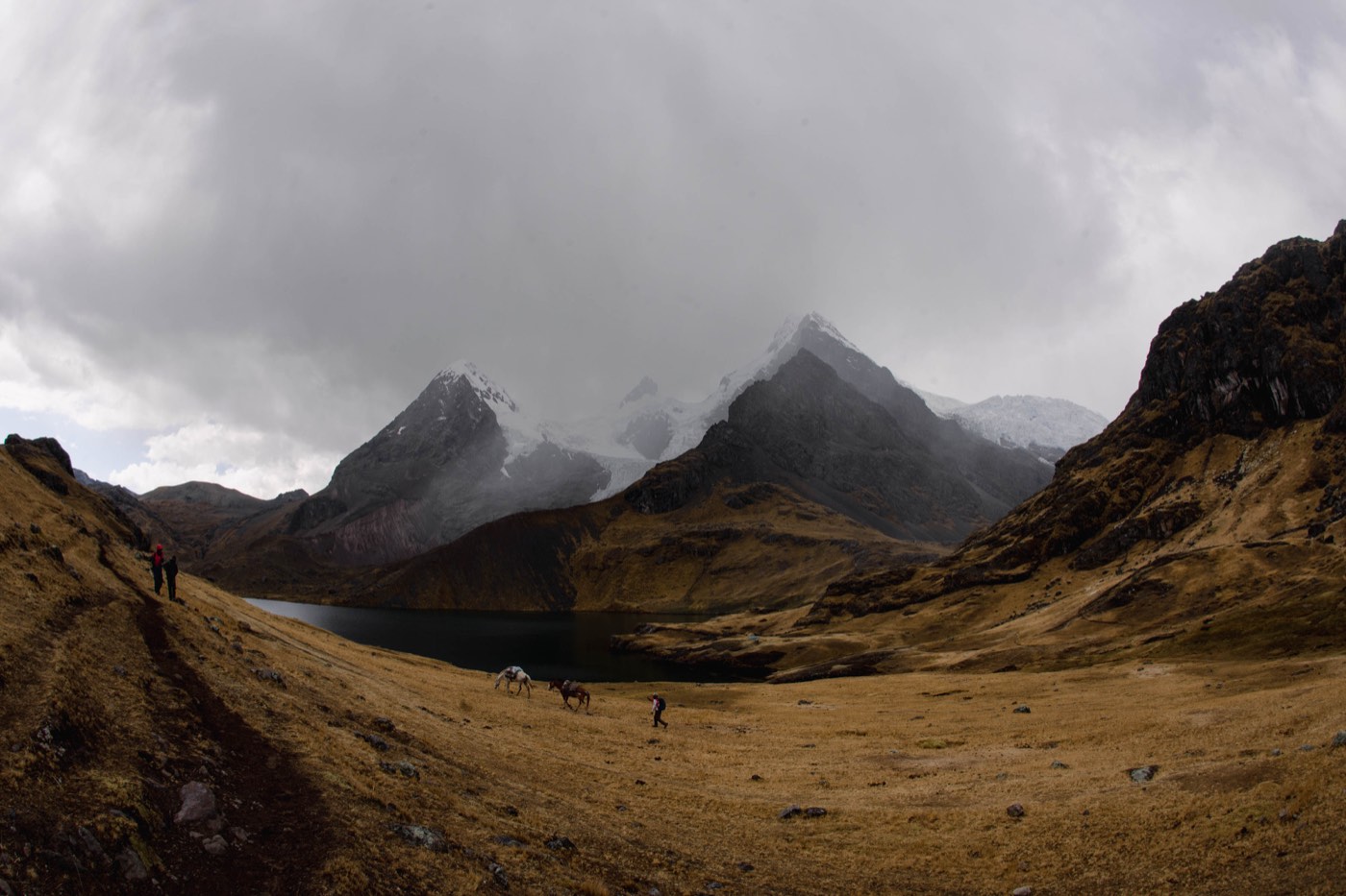 Laguna de montaña rodeada por cumbres y laderas de los Andes.